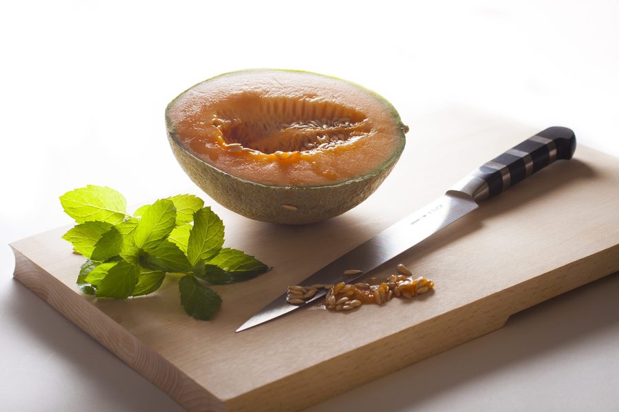 Aufgeschnittene Melone mit frischer Minze auf einem Holzbrett